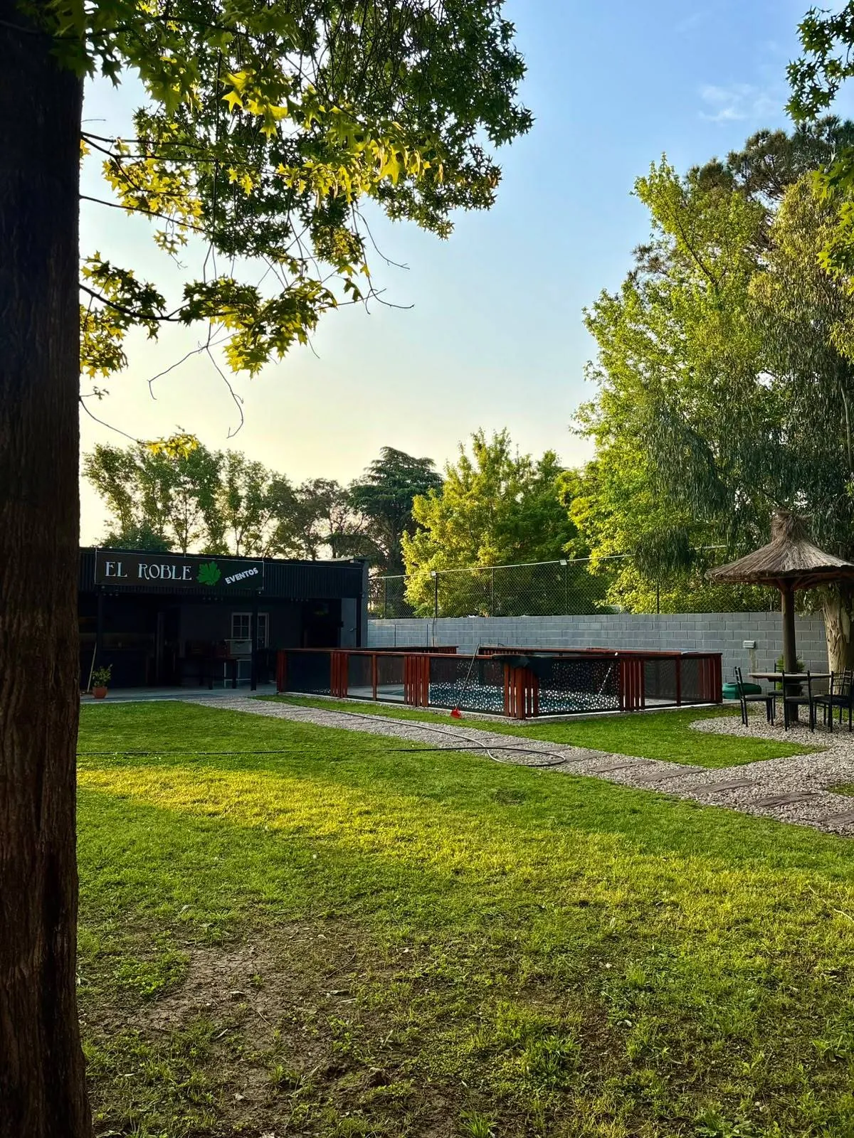 Parque con césped, árboles y el quincho de El Roble